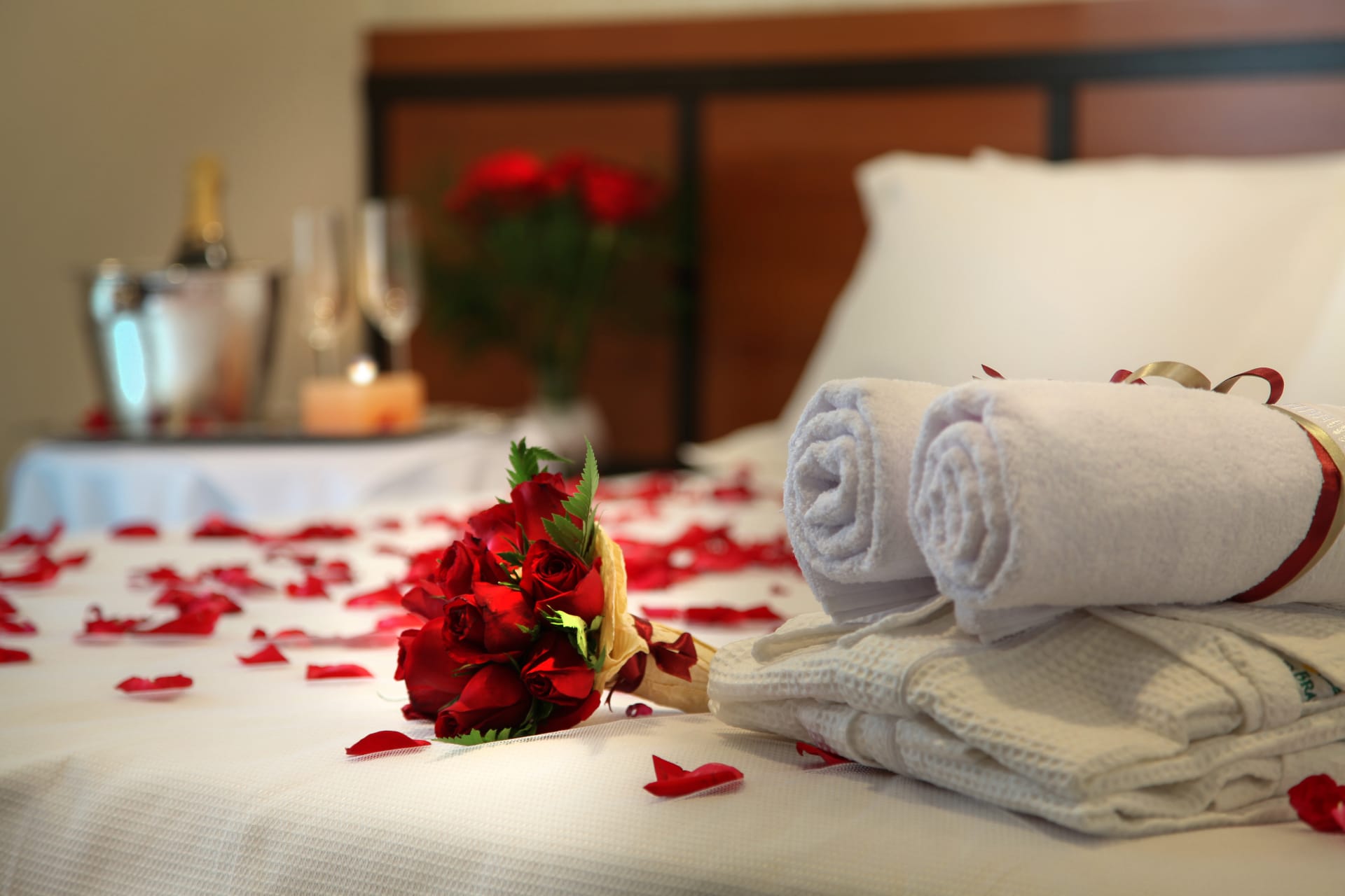 towels, bathrobes and roses on a hotel bed